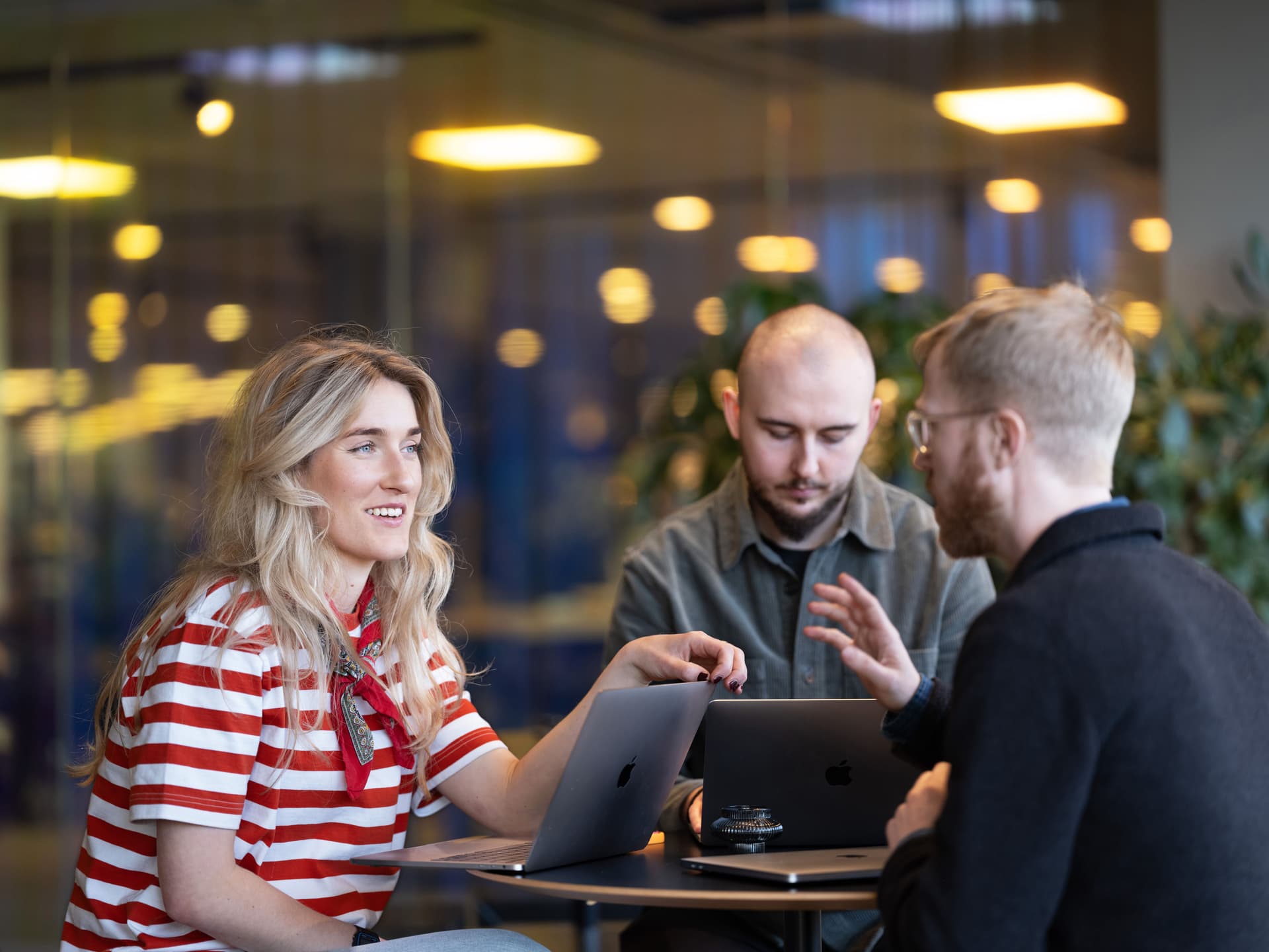 Tre kollegor har ett möte i ett ljust, modernt kontorslandskap.